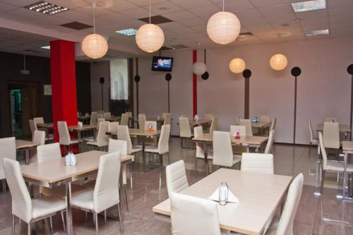 une salle à manger avec des tables, des chaises blanches et des lumières dans l'établissement Grand City Hotel, à Chita
