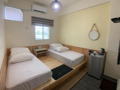 two beds in a room with a mirror and a clock at 玖拾捌民宿-98bnb in Hualien City
