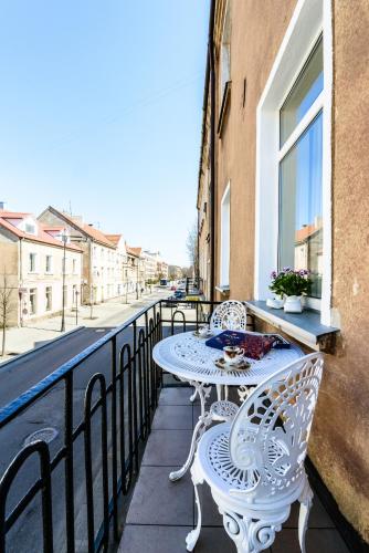 biały stół i dwa krzesła na balkonie w obiekcie Nostalgia Apartment w Kłajpedzie