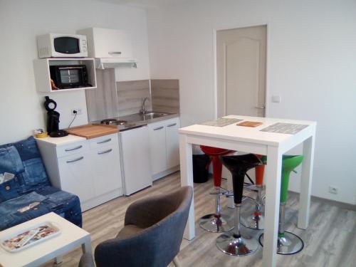 een kleine keuken met een witte tafel en stoelen bij Studio neuf tout confort très calme in Beuvrages