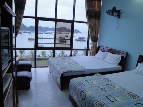 two beds in a room with a large window at Phuong Mai Family Hotel in Cat Ba