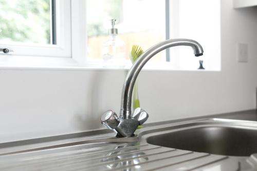 a kitchen sink with a faucet next to a window at Hertford Serviced Apartments by Payman Club in Hertford