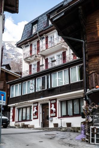 a large white building with balconies on a street at Weisses Rössli in Leukerbad