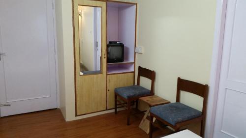 a room with two chairs and a mirror and a television at Flyer Exotica in Shimla