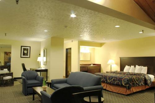 a hotel room with a bed and two chairs at Best Western Richland Inn Mansfield in Mansfield