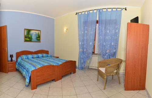 a bedroom with a bed with blue curtains and a chair at Villa Benice in Morino