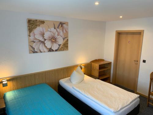 a small room with a bed and a table and a painting at Landhotel & Restaurant "Fahrenkamp" in Röwitz