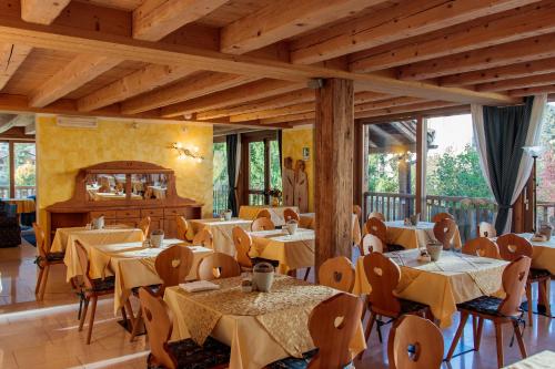 een restaurant met tafels en stoelen in een kamer met ramen bij Casa Moresc in Spiazzo
