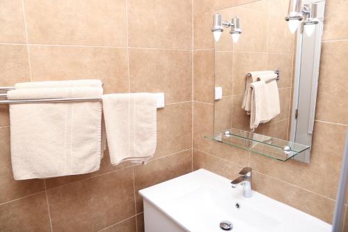 uma casa de banho com lavatório, espelho e toalhas em Karioca Management em Paço de Arcos