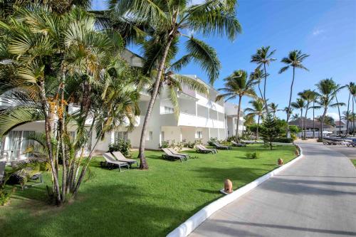 a building with palm trees and chairs on the lawn at Occidental Punta Cana - All Inclusive in Punta Cana
