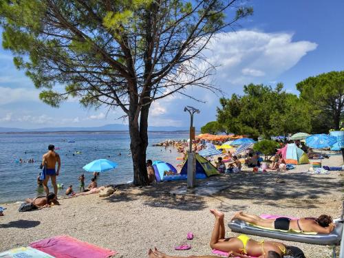 a crowd of people on a beach with umbrellas at Ivana apartman 3 in Crikvenica