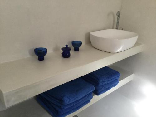 a bathroom with a sink and blue towels on a shelf at MAMMA MIA On THE BEACH in Pefkali