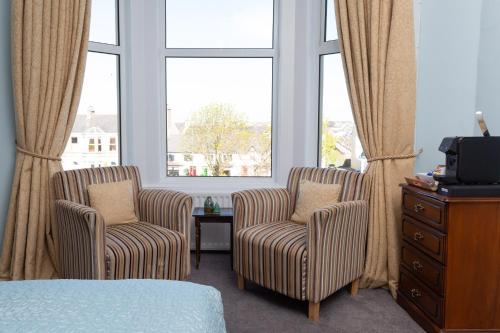 two chairs and a dresser in a room with windows at Shelleven Guest House in Bangor