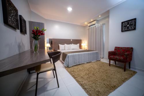 a hotel room with a bed and a red chair at Hotel Porto Madeira in Porto Velho