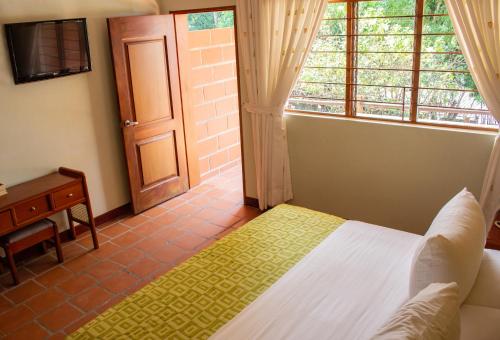 a bedroom with a bed and a window and a door at Hosteria Guaracú in San Jerónimo