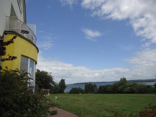 a yellow building with a balcony on the side of a field at Inselhotel kleiner Bodden in Buschvitz