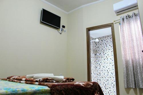 um quarto com uma cama e uma televisão na parede em Pousada Renascer II em Cachoeira Paulista