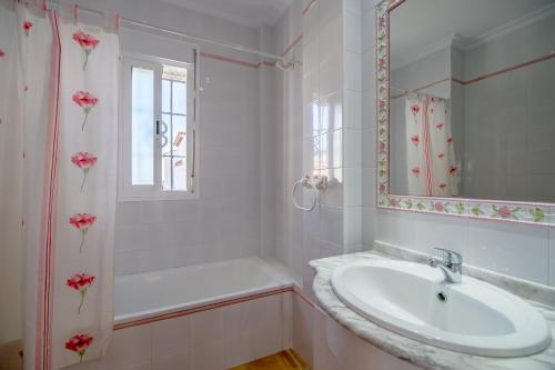 een badkamer met een wastafel, een bad en een spiegel bij Chalet adosado Atalaya F in Conil de la Frontera