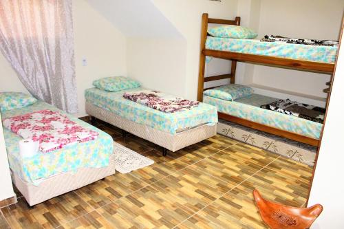 a room with three bunk beds and a wooden floor at Pousada Renascer II in Cachoeira Paulista