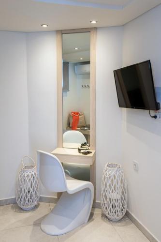 a room with a white chair and a tv on a wall at Estian Deluxe in Limenaria