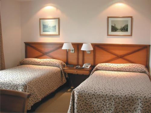 Habitación de hotel con 2 camas y teléfono en Elegance Hotel en Tres Arroyos