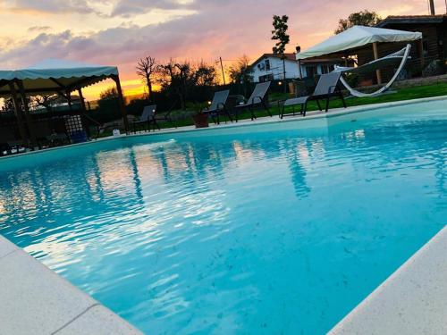- une piscine au coucher du soleil avec des chaises et un toboggan dans l'établissement Agriturismo Quercetelli, à Castiglione del Lago