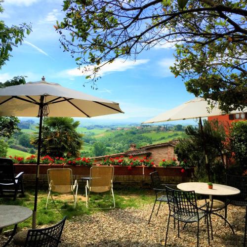 a patio with tables and chairs and an umbrella at Hotel Santa Caterina in Siena