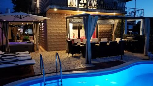 a pool with a table and chairs and a patio at Villa Summer dream with heated pool, sauna and jacuzzi in Malinska