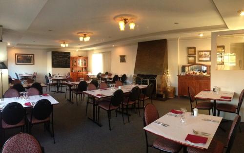 uma sala de jantar cheia de mesas e cadeiras em Colonial Motor Lodge Scone em Scone
