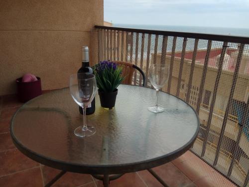 Una mesa con dos copas de vino y una botella de vino. en torre Azafata, en Arenales del Sol