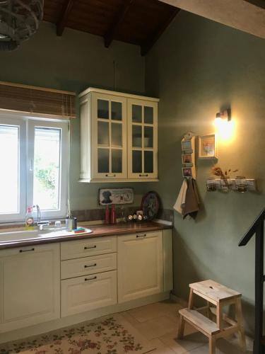 a kitchen with green walls and white cabinets and a stool at Plane Tree House in Mákri