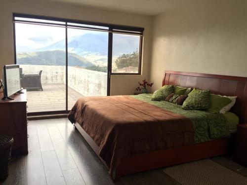 1 dormitorio con 1 cama y vistas a un balcón en La Casa del Lago, en Otavalo