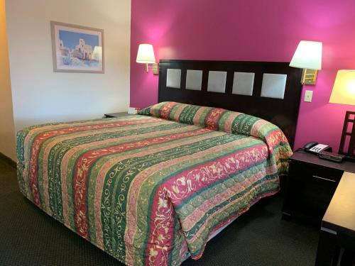 a hotel room with a bed and purple walls at Luxury Inn in Albuquerque