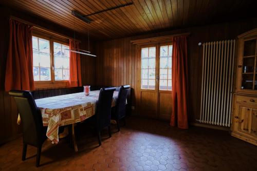 a dining room with a table and chairs and windows at Chalet Floriana in Les Diablerets
