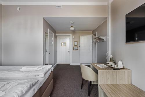 a hotel room with a bed and a desk and a table at Livgrenadjärmässen Hotell-Fest-Konferens in Linköping
