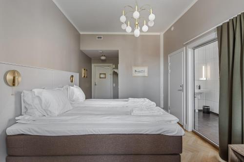 a large white bed in a bedroom with a chandelier at Livgrenadjärmässen Hotell-Fest-Konferens in Linköping