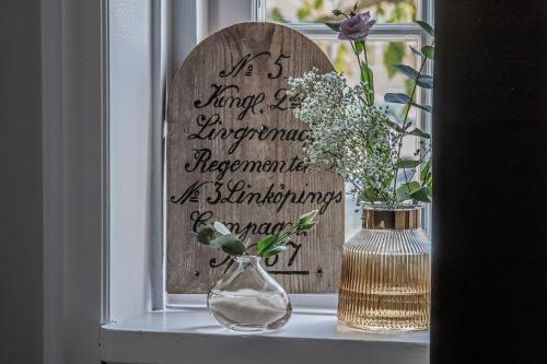 a window sill with a vase of flowers and a sign at Livgrenadjärmässen Hotell-Fest-Konferens in Linköping
