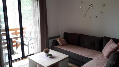 a living room with a couch and a table and a clock at Apartman Nana Svetogorska 19 ,stan 17 in Zlatibor