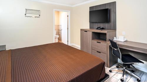 a hotel room with a bed and a desk and a television at Sea Rock Inn - Long Beach in Long Beach