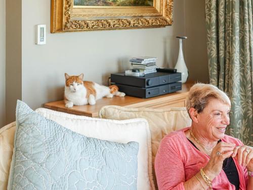 an older woman sitting on a couch with a cat at Dyers House in Christchurch