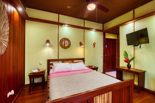 a bedroom with a bed and a flat screen tv at Hotel Banana Azul - Adults Only in Puerto Viejo