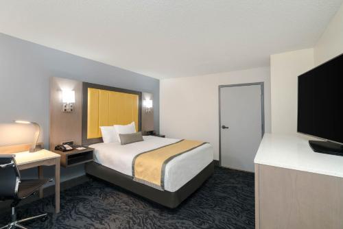 a hotel room with a bed and a desk and a television at Baymont by Wyndham Franklin in Franklin