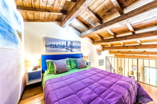 a large purple bed in a room with wooden ceilings at Mari e Luci in Nurachi