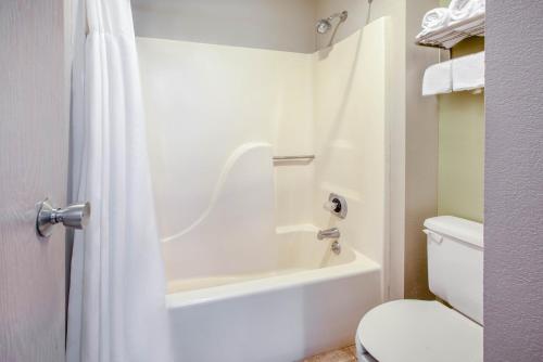a bathroom with a white tub and a toilet at Baymont by Wyndham Grand Rapids Airport in Grand Rapids