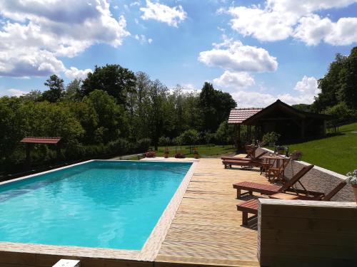 a swimming pool with a wooden deck and benches next to it at Grebengradska Medna Hiža in Donje Makojišće
