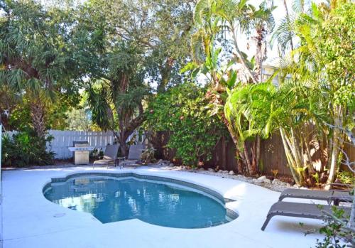 a swimming pool in a yard with chairs and trees at Crescent Beach 1011 #1 in Sarasota
