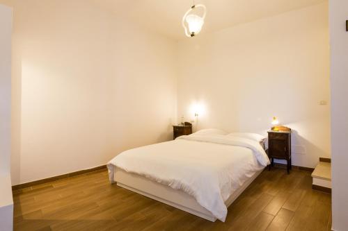 a white bedroom with a bed and a night stand at Room En Suite la Corte Assisi in Assisi