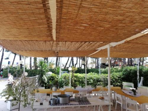 a restaurant with tables and chairs under a wooden umbrella at Hotel Petit in Silvi Marina