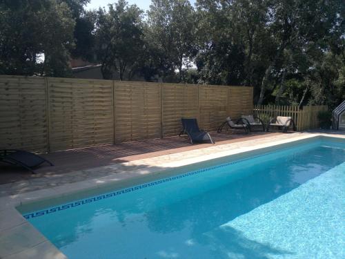 - une piscine avec 2 chaises et une clôture en bois dans l'établissement A l'Est d'Uzès, à Saint-Siffret