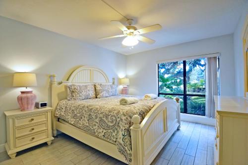 een slaapkamer met een bed, een plafondventilator en een raam bij Bay Oaks - 6157 #E01 in Siesta Key